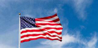 American flag waving against a blue sky.