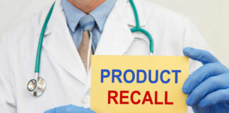Doctor holding a product recall sign in gloves