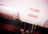 A typewriter with a paper displaying the words 'TAXES AHEAD'
