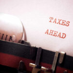 Billionaire Exodus: California Tax Bomb A typewriter with a paper displaying the words 'TAXES AHEAD'