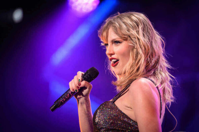 Taylor Swift performing with microphone on stage, colorful lighting.