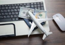 A model airplane on a laptop keyboard with a passport and cash