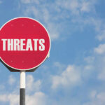 Red sign with the word threats against sky