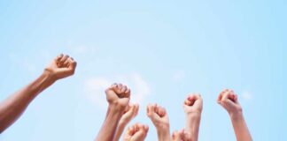 Multiple raised fists against a blue sky