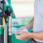 Man holding cash at a gas station