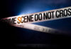 Police tape reading 'CRIME SCENE DO NOT CROSS' in a dark setting