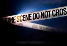Police tape reading 'CRIME SCENE DO NOT CROSS' in a dark setting