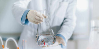 Scientist holding a flask filled with liquid in a laboratory setting