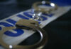 Close-up of handcuffs resting on a police-themed background