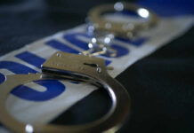 Close-up of handcuffs resting on a police-themed background
