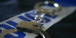 Close-up of handcuffs resting on a police-themed background