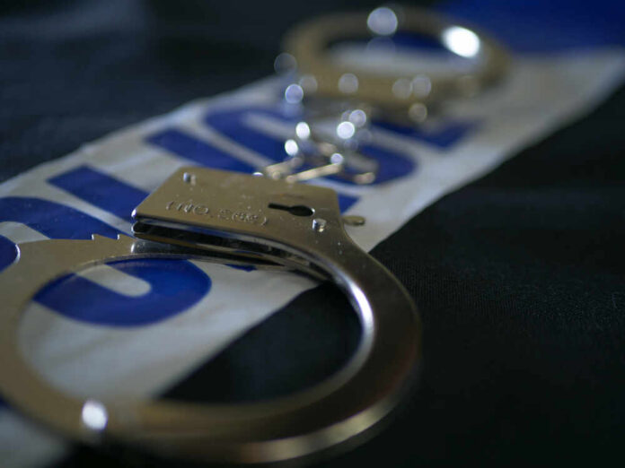 Close-up of handcuffs resting on a police-themed background