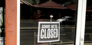 Closed sign hanging on a glass door