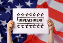 Hands holding impeachment sign over American flag.