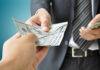 A person handing over a stack of cash to another individual in a suit