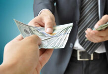 A person handing over a stack of cash to another individual in a suit