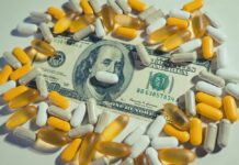 A one hundred dollar bill surrounded by various capsules and pills