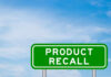 Green sign with product recall text and sky background
