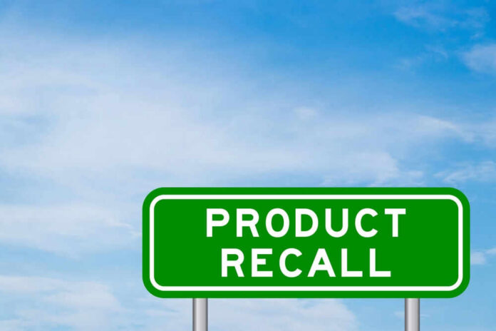 Green sign with product recall text and sky background