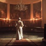 A religious figure standing in a church with candlelight illuminating the space