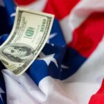 A hundred dollar bill resting on an American flag