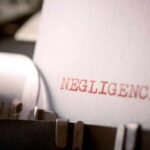 Close-up of a typewriter with the word 'NEGLIGENCE' typed on a sheet of paper