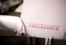 Close-up of a typewriter with the word 'NEGLIGENCE' typed on a sheet of paper