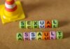 Colorful letter blocks spelling out 'SEXUAL' and 'ASSAULT' next to a traffic cone