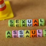 Colorful letter blocks spelling out 'SEXUAL' and 'ASSAULT' next to a traffic cone