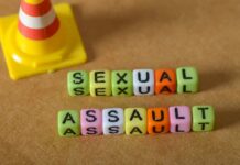 Colorful letter blocks spelling out 'SEXUAL' and 'ASSAULT' next to a traffic cone