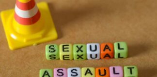 Colorful letter blocks spelling out 'SEXUAL' and 'ASSAULT' next to a traffic cone