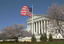 U.S. Supreme Court building with an American flag and cherry blossom trees