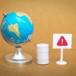 Critical Chokepoint WEAPONIZED — Global Economy Stalling A miniature globe next to a warning sign and a barrel