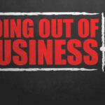 A hand writing 'GOING OUT OF BUSINESS' on a chalkboard