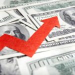BOMBSHELL: Interest Costs TRIPLE in Just Six Years A red arrow indicating growth over scattered hundred dollar bills