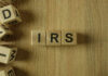 Wooden blocks arranged to spell 'IRS' on a wooden surface