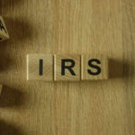Wooden blocks arranged to spell 'IRS' on a wooden surface