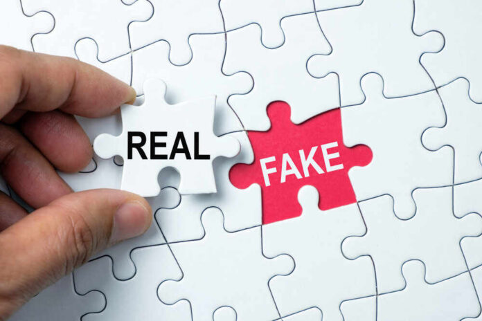 shutterstock_1403469443.jpg A hand holding a white puzzle piece labeled 'REAL' next to a red puzzle piece labeled 'FAKE'