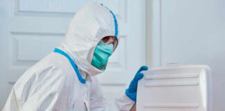 Healthcare worker in protective gear disposing of waste