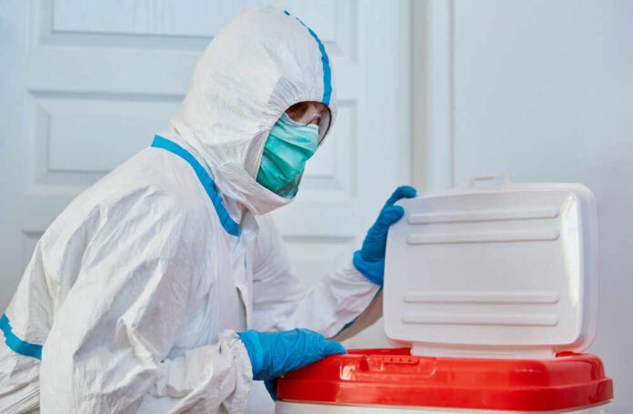 Surgeon,In,Protective,Clothing,In,Clinic,Before,Heart,Transplant,With Healthcare worker in protective gear disposing of waste
