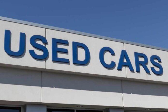 shutterstock_2137694767.jpg Sign displaying 'USED CARS' on a dealership building