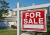 A 'For Sale' sign in front of a house
