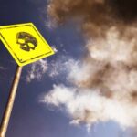 Yellow warning sign with skull symbol under dramatic cloudy sky