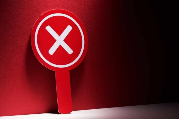 Red sign with a white 'X' symbol against a dark background