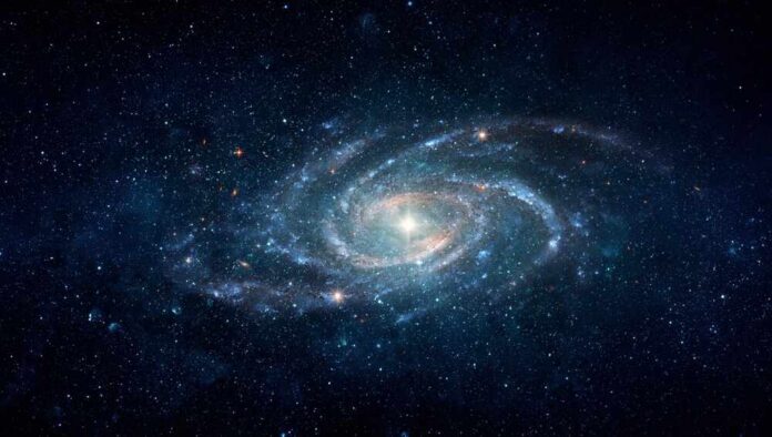 shutterstock_2737449053.jpg A spiral galaxy surrounded by stars in a dark space background