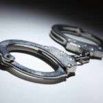 Elite Agent Arrested Hours After Guarding Trump Close-up of metallic handcuffs on a light surface