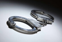 Close-up of metallic handcuffs on a light surface