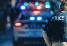 Bloody Weekend Ignites Washington Showdown Police officer stands near patrol car with lights flashing.