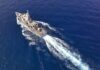 Aerial view of a naval ship navigating through the ocean