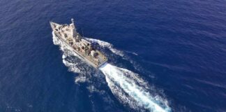 Aerial view of a naval ship navigating through the ocean